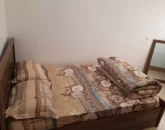 تخت خواب با روتختی قهوه ای و آیینه اتاق خواب آپارتمان در قائم شهر