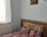 تخت خواب با روتختی رنگی و پنجره با پرده سفیداتاق خواب آپارتمان در نکا