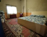 تخت خواب با روتختی رنگی و بخاری اتاق خواب خانه روستایی در خورشید کلا