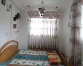 تخت خواب با روتختی سبز رنگ و پرده های رنگی اتاق خواب خانه روستایی در ساری