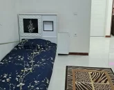 تخت خواب با روتختی سورمه ای رنگ و فرش کرمی اتاق خواب ویلا در جویبار