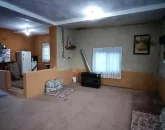 پشتی و بخاری و پرده سفید پنجره سالن نشیمن خانه روستایی در خورشیدکلا