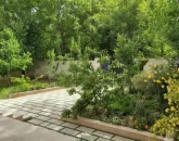 محوطه سنگ فرش شده و باغچه سرسبز محوطه ویلا در جویبار