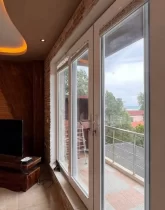 ویو رو به ویلاهای اطراف و درختان سرسبز تراس آپارتمان در جویبار