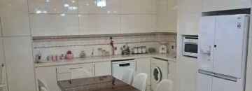 میز غذاخوری و یخچال و لباسشویی و سقف نورپردازی شده آشپزخانه آپارتمان در خورشیدکلا