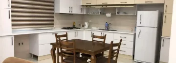 میز غذاخوری و کابینت های سفید و یخچال آشپزخانه آپارتمان در قائم شهر