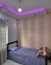 تخت خواب و کاغذ دیواری و پرده طوسی رنگ و سقف نور پردازی شده با نور بنفش اتاق خواب ویلا در ساری