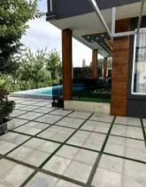 محوطه سنگ فرش شده و باغچه ی سرسبز با گل های رنگارنگ ویلا در نکا