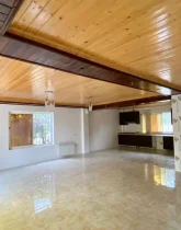 سالن نشیمن با سقف کاذب چوبی و نمایی از آشپزخانه ویلای 310 متری در زاغمرز 1358416878