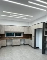 کابینت های کرمی رنگ و سقف نور پردازی شده با نور سفید آشپزخانه ویلا در جویبار