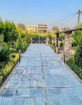 محوطه سنگ فرش شده و باغچه سرسبز محوطه ویلا در طاهرآباد